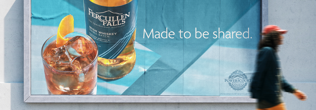 A man walking by a Fercullen Falls billboard that says, Made to be shared.